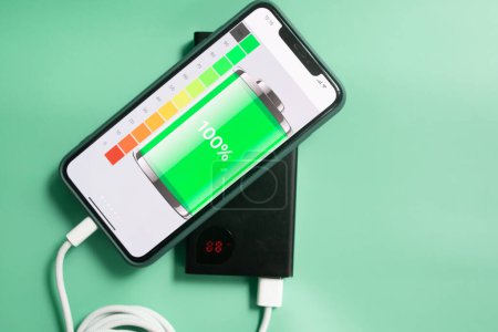 Photo for Portable charger charging a smartphone isolated on a green background. Power bank. - Royalty Free Image