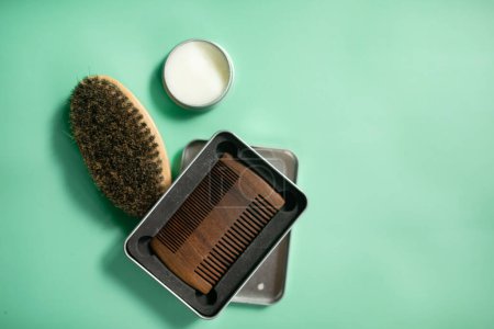 Photo for Barber shop tools on green background. Vintage wooden beard comb, beard oils, scissors, electric trimmer, brush and balm. - Royalty Free Image