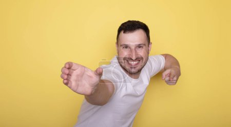 Foto de Retrato de un joven en una camiseta blanca posando en un estudio sobre un fondo amarillo. - Imagen libre de derechos