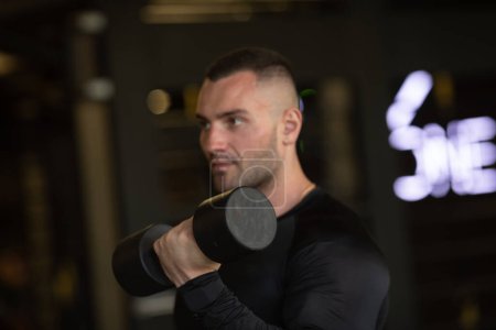 Photo for Fit young man in sportswear lifting weight during an exercise class in a gym. - Royalty Free Image