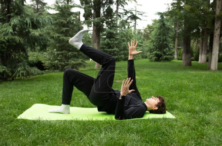 Photo for Man exercising outdoors in the garden training on a yoga mat. Exercise for health. Yoga. - Royalty Free Image