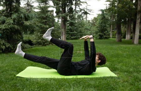Photo for Man exercising outdoors in the garden training on a yoga mat. Exercise for health. Yoga. - Royalty Free Image