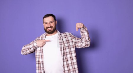 Photo for Handsome bearded trendy stylish confident positive cheerful man pointing on blank copy space, over pastel violet purple background - Royalty Free Image
