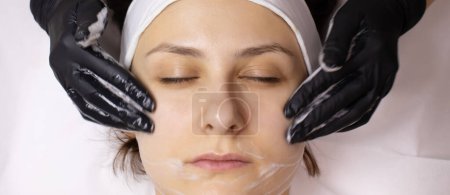 Foto de Lavar y secar la cara de una clienta antes de los procedimientos de cosmetología. - Imagen libre de derechos