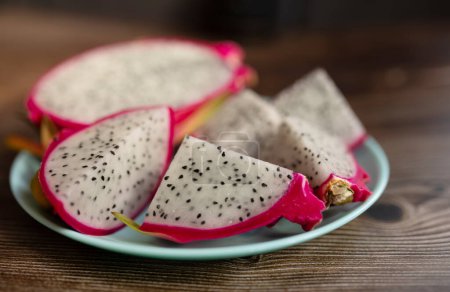 Photo for Close-up view of sliced dragon fruit, exotic dragon fruit on plate on wooden table background. Pitahaya. - Royalty Free Image