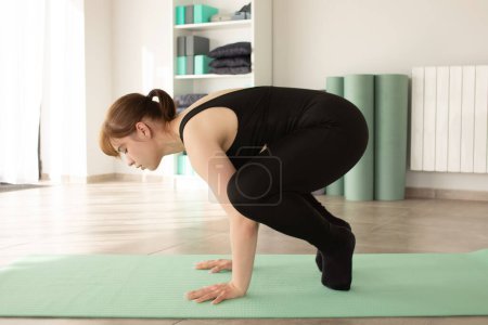 Téléchargez les photos : Jeune femme attrayante pratiquant le yoga à l'intérieur. Femme pratiquant dans un club de fitness. Concept de yoga. Mode de vie. - en image libre de droit