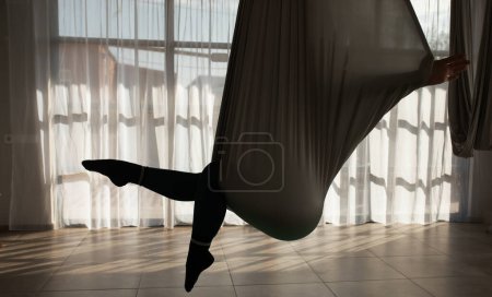 Téléchargez les photos : Jeune femme pratiquant le yoga de mouche dans la salle de gym. Entraîneur de yoga aéro tenant des sangles dans les mains. - en image libre de droit