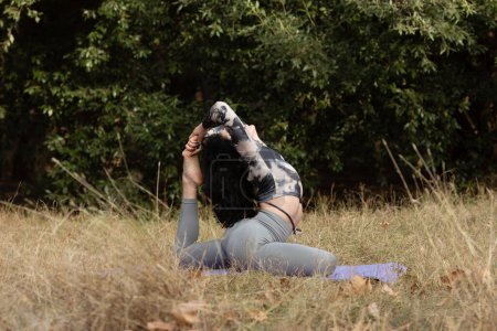 Foto de Mujer bonita haciendo ejercicios de yoga en el parque de otoño. Hermosa mujer practicando yoga sola en el bosque. - Imagen libre de derechos