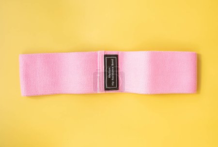 Foto de Vista superior de banda elástica rosa para fitness sobre fondo amarillo. Concepto deportivo. Tendencia fitness. - Imagen libre de derechos