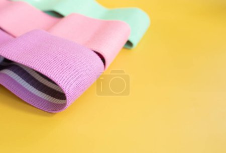 Téléchargez les photos : Ensemble de bandes colorées de résistance de la hanche pour la forme physique sur fond jaune. concept sportif. - en image libre de droit
