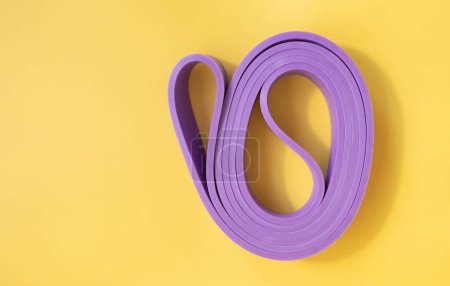 Photo for Top view of purple rubber band for fitness on yellow background. Sports concept. Fitness trend. - Royalty Free Image