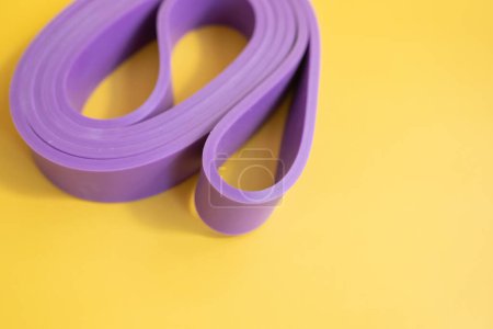 Photo for Top view of purple rubber band for fitness on yellow background. Sports concept. Fitness trend. - Royalty Free Image