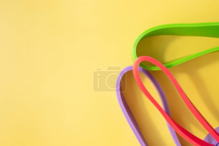 Téléchargez les photos : Ensemble de bandes de caoutchouc colorées pour la forme physique sur fond jaune. concept sportif. - en image libre de droit