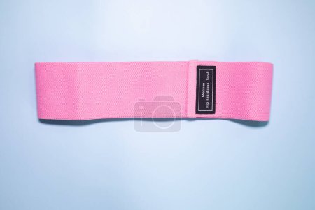 Foto de Vista superior de banda elástica rosa para fitness sobre fondo azul. Concepto deportivo. Tendencia fitness. - Imagen libre de derechos