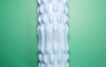 Foto de Primer plano del rodillo de espuma de masaje azul sobre fondo verde. - Imagen libre de derechos