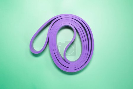Foto de Bandas de goma púrpura para fitness sobre fondo verde. concepto deportivo. - Imagen libre de derechos