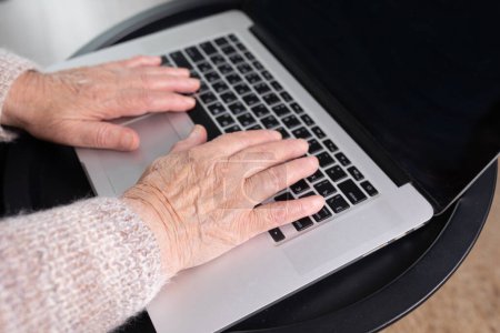 Foto de Vista de cerca de la mujer de edad avanzada utilizando el ordenador en la oficina en casa. Concepto de trabajo remoto. Las mujeres mayores compran en línea, pasan tiempo libre en Internet, disfrutan de la comunicación en las redes sociales, descansan en casa. - Imagen libre de derechos