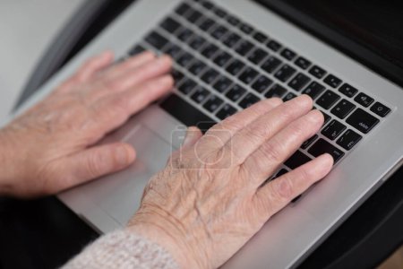 Photo for Close-up view of elderly woman using computer at home office. Remote work concept. Senior woman buy on-line, spend free time on internet, enjoy communication in social media, resting at home. - Royalty Free Image