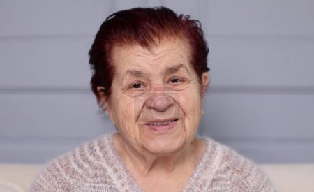 Téléchargez les photos : Gros plan portrait de belle dame âgée regardant la caméra alors qu'elle était assise à la maison - en image libre de droit