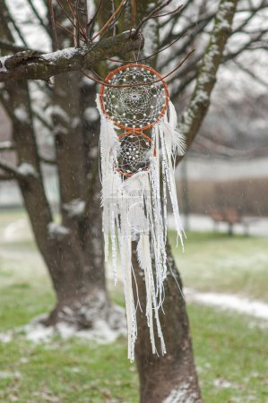 Photo for Handmade white dreamcatcher with lace, feathers close up tribal bohemian craft tree hanging outdoors, winter weather wind, rain and snow - Royalty Free Image