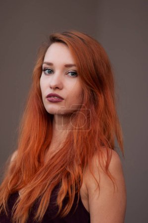 Photo for Close-up portrait of beautiful haughty slim girl with long red hair looking in the camera cold look - Royalty Free Image