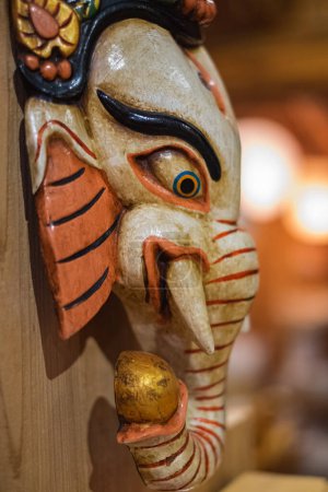 Foto de La Madera de ganesha aislada sobre fondo de madera. Colorida tradición máscaras de madera y artesanías a la venta en la tienda. Nadie, borroso, enfoque selectivo - Imagen libre de derechos
