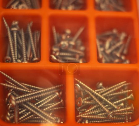 Photo for Plastic transparent organizer with screws, dowels, drills. Screws and nails in orange plastic box. Plastic organizer box with wood screws and nails. Accessories for woodwork. Blurred, nobody - Royalty Free Image
