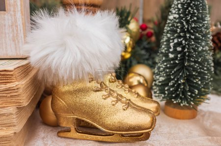 Photo for Two figure ice skates Christmas decor. Pair of golden skate shoes with fir. Vintage wintertime holidays. Skates on the top of fireplace. Christmas decoration. Nobody - Royalty Free Image