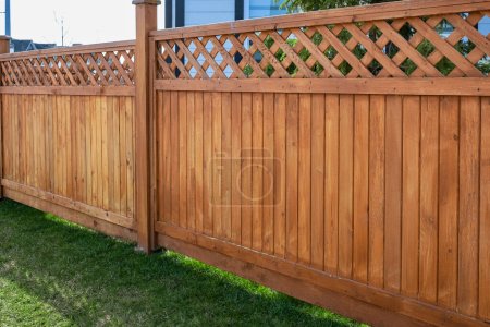 Photo for Nice new wooden fence around house. Wooden fence with green lawn. Street photo, nobody, selective focus - Royalty Free Image