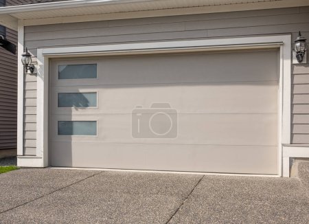 Téléchargez les photos : Porte de garage dans une maison de luxe à Vancouver, Canada. Un quartier parfait. Maison familiale avec large porte de garage et allée en béton devant. Personne, photo de rue, espace de copie pour le texte - en image libre de droit