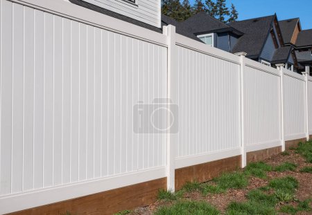 Téléchargez les photos : Belle nouvelle clôture en bois autour de la maison. Clôture blanche en bois avec pelouse verte. Photo de rue, personne, mise au point sélective - en image libre de droit