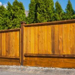 Nice new wooden fence around house. Wooden fence. Street photo, nobody, selective focus. Real Estate Exterior Front House on a sunny day