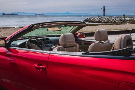 Photo for Red convertible car with the top down stopped on the beach. Closeup view of luxury convertible car interior. Nobody, selective focus, street photo. - Royalty Free Image