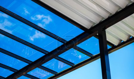 Pergola aus Aluminium für die Außenterrasse vor blauem Himmel. Ansicht von unten. Aufnahme einer Pergola im Innenhof vor dem Hintergrund eines schönen klaren Himmels, selektiver Fokus,