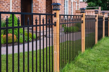 Wrought Iron Fence. Metal black fence around house with green lawn. Street photo, nobody Poster 663700566