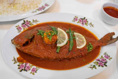 Téléchargez les photos : Maragat Zubaidi Plat de poisson avec saucisse de tomate dans une assiette, curry de poisson Seer, curry de poisson traditionnel, plat spécial. Poisson à la pommade argentée avec saucisse rouge plat asiatique traditionnel du Moyen-Orient. Personne, vue du dessus - en image libre de droit
