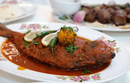 Téléchargez les photos : Maragat Zubaidi Plat de poisson avec saucisse de tomate dans une assiette, curry de poisson Seer, curry de poisson traditionnel, plat spécial. Poisson à la pommade argentée avec saucisse rouge plat asiatique traditionnel du Moyen-Orient. Personne, vue du dessus - en image libre de droit