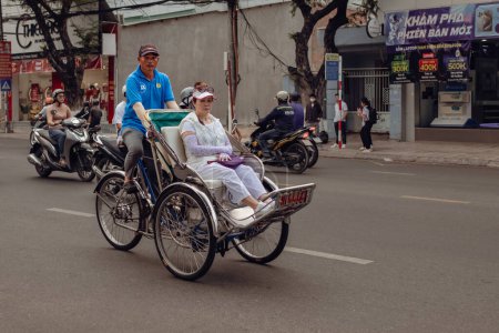 Foto de Nha Trang Vietnam Taxi servicio de triciclo turistas en bicicleta por la ciudad. Trabajador vietnamita montar en bicicleta carro de triciclo rickshaw para los viajeros de servicio. Cyclo es la mayoría de los vehículos favoritos-marzo 28,2024 - Imagen libre de derechos