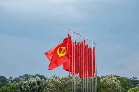 Téléchargez les photos : Grand drapeau communiste flottant dans le vent avec un fond bleu ciel. Drapeau rouge soviétique agitant dans la journée venteuse en Asie, Vietnam - en image libre de droit