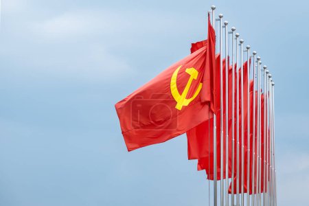 Téléchargez les photos : Grand drapeau communiste flottant dans le vent avec un fond bleu ciel. Drapeau rouge soviétique agitant dans la journée venteuse en Asie, Vietnam - en image libre de droit
