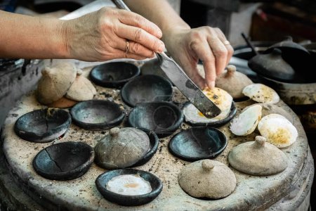 Vietnamese mini fried eggs, with rice flour, cooking on the street. Asian woman preparing Traditional Vietnamese breakfast. Banh can is a popular dish in the Central Highlands city Da Lat Vietnam