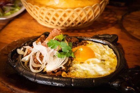 Bo ne trung, Rindfleisch gekocht in einer heißen Platte mit Soße und Eier vietnamesischen Frühstück. Bo Ne, ein traditionelles vietnamesisches Frühstück mit Steak, Eiern und Baguette