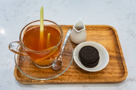 Téléchargez les photos : Tasse de thé au gingembre avec citronnelle et miel et biscuits. Coupe en verre de thé au gingembre chaud avec racine de rhizome de gingembre tranchée. Herbes et épices. Thé au gingembre sain - en image libre de droit