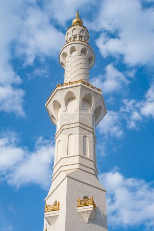 The white minaret of a Mosque with blue sky. Mosque minaret, blue sky background. Detail of Sheikh Zayed Grand Mosque on the blue sky background