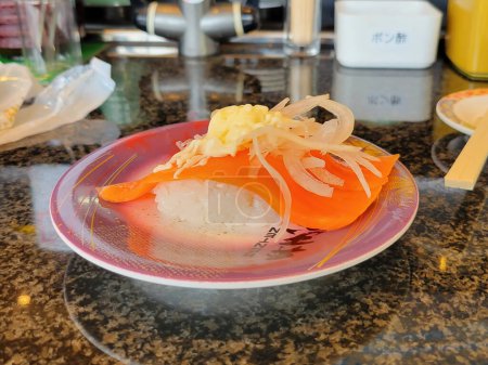 Ein köstliches Stück frisches Lachssushi, das in einem traditionellen japanischen Restaurant in Japan serviert wird. Die lebendigen Farben und die aufwändige Präsentation machen dieses Gericht zu einem Augenschmaus.