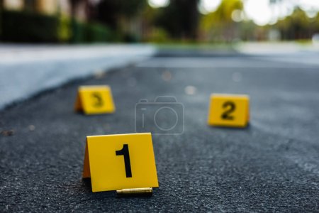 Photo for A group of yellow crime scene evidence markers on the street after a gun shooting brass bullet shell casing rifle - Royalty Free Image