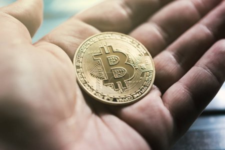 Foto de Mano sosteniendo un color dorado bitcoin moneda moneda digital criptocurrenia token - Imagen libre de derechos