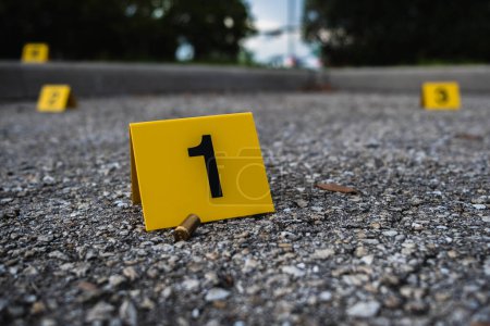 Foto de Un grupo de marcadores de evidencia amarilla de la escena del crimen en la calle después de que un arma disparara un rifle carcasa de bala de bronce - Imagen libre de derechos