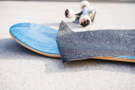 Téléchargez les photos : Appliquer du ruban adhésif sur un tout nouveau pont de skateboard à côté d'un ensemble de camions et de roues - en image libre de droit