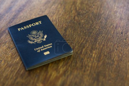 Un passeport américain bleu posé sur un bureau en bois